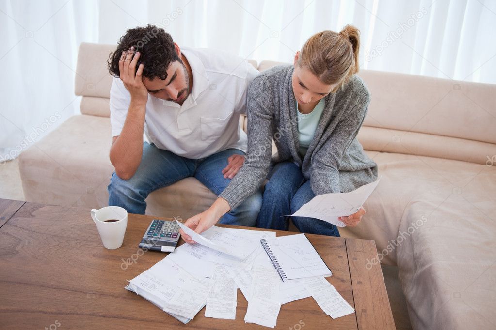 Stressed Couple Sitting At Table Going Through Papers