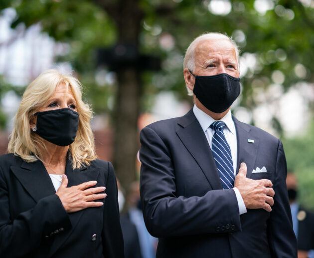 Joe And Jill Biden Standing With Hands Over Heart Wearing Masks