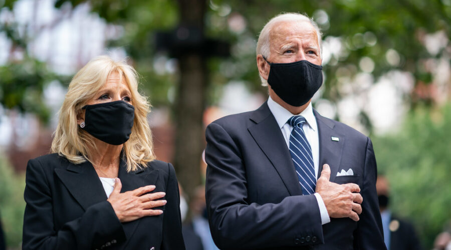 Joe And Jill Biden Standing With Hands Over Heart Wearing Masks
